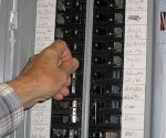 Turning a circuit breaker off in an electrical service panel.