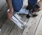 Drilling holes in a plastic soft drink bottle to make a homemade sprinkler.