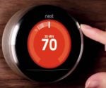 Hand adjusting a Nest Learning Thermostat to 70 degrees.