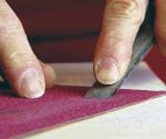 Using sandpaper to sharpen a chisel.