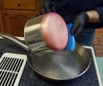 Wiping copper bottom of pot with sponge dipped in hot vinegar and sprinkled with salt to clean it.