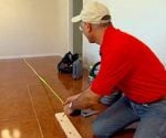 Measuring the floor length in a room with a tape measure and reference board