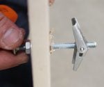 Installing a toggle bolt in a drywall wall.