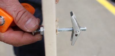 Installing a toggle bolt in a drywall wall.