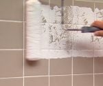 Rolling paint on a ceramic tile wall.
