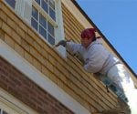 Man on ladder painting house exterior